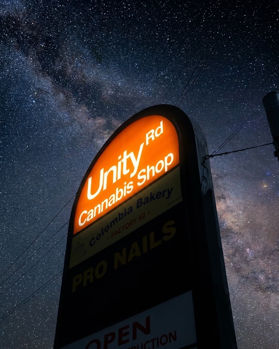 The illuminated Unity Rd Cannabis Shop sign under a starry night sky